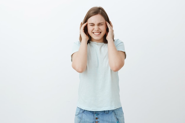 Foto grátis ela não consegue lidar com a pressão durante o semestre. mulher intensa descontente com dor de cabeça, enxaqueca cerrando os dentes de dor e fechando os olhos de mãos dadas nas têmporas tentando se concentrar, desorientada