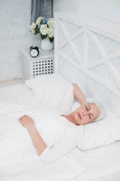 Elder mulher dormindo em uma cama branca