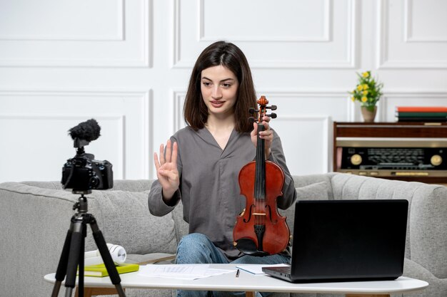 Elearning jovem linda e bonita remotamente em casa dando aulas de violino falando na câmera