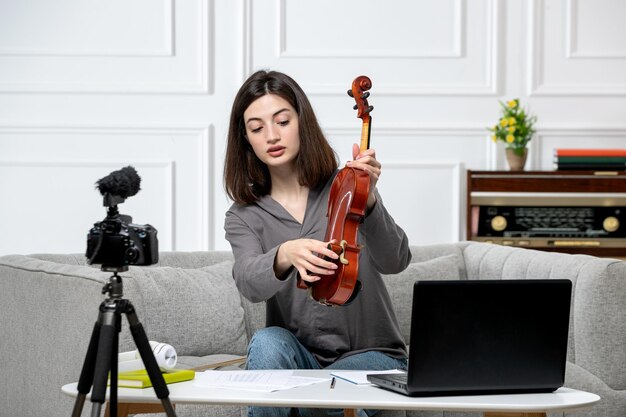 Elearning jovem linda e bonita remotamente em casa dando aulas de violino mostrando como tocar