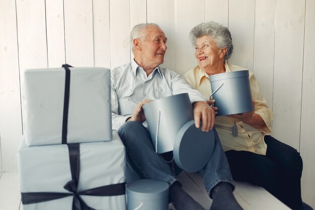 Elegante casal velho sentado em casa com presentes de Natal