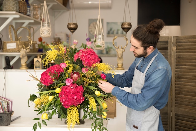 Foto grátis elegante florista masculina criar buquê de flores na mesa da loja