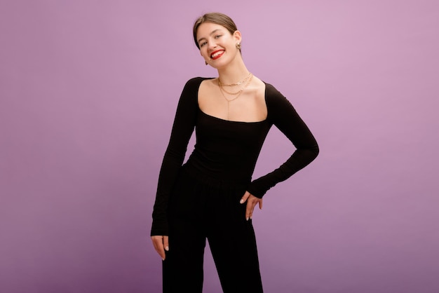 Elegante jovem morena caucasiana com lábios vermelhos em roupas pretas sobre fundo roxo Conceito de lazer de emoções diferentes estilo de vida