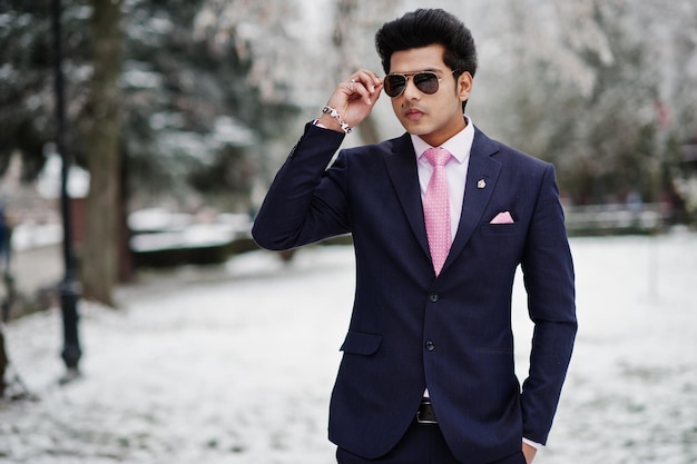 Elegante modelo de homem macho indiano de terno e óculos de sol de gravata rosa posou no dia de inverno