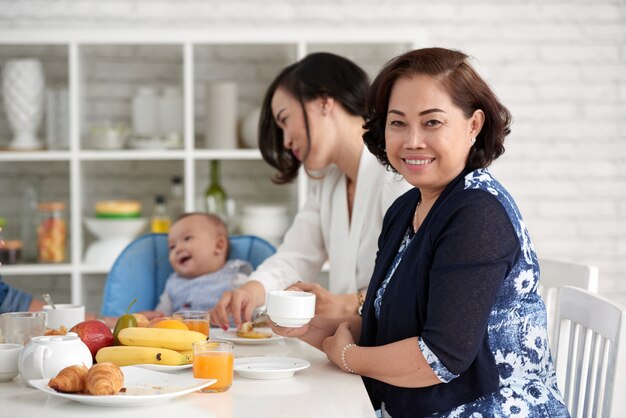 Elegante mulher asiática na mesa de café da manhã com a família