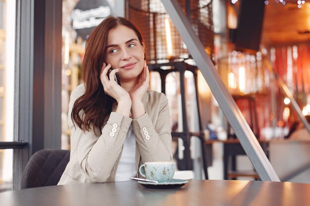 Elegante mulher sentada à mesa com um telefone