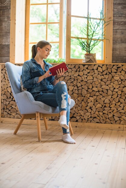 Elegante mulher sentada na cadeira e lendo o livro