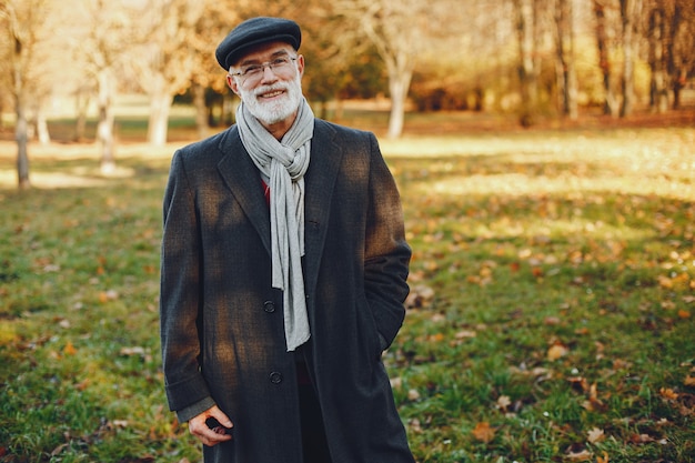 Elegante velho em um parque ensolarado de outono