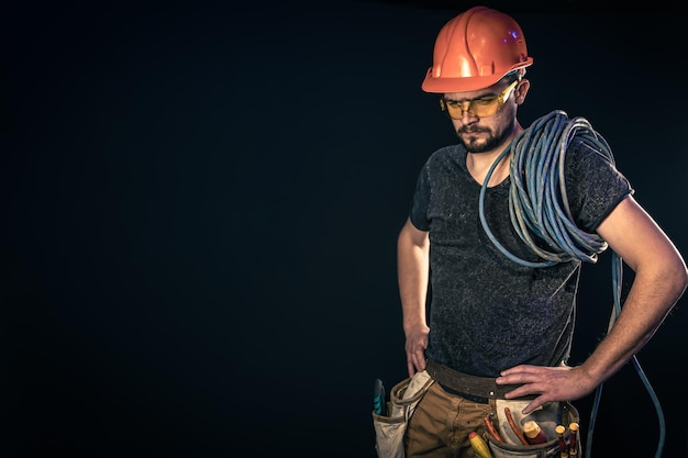 Eletricista masculino com cabo elétrico em um espaço de cópia de fundo preto