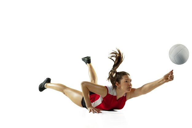 Em salto e vôo. Jovem jogadora de voleibol isolada no fundo branco do estúdio. Mulher em roupas esportivas e tênis, treinando, jogando. Conceito de esporte, estilo de vida saudável, movimento e movimento.