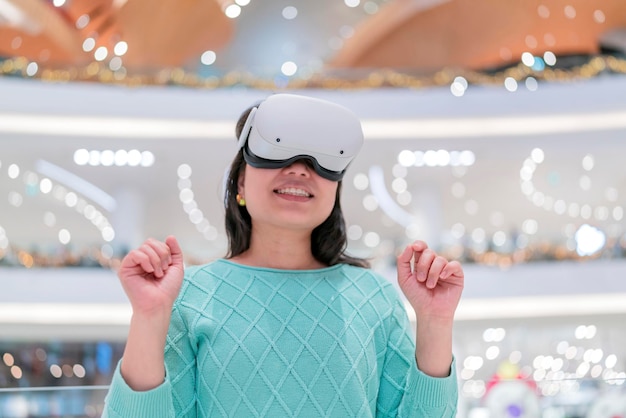 Emocionante mulher asiática usando fone de ouvido vr obtendo experiência usando óculos vrheadset andando pelo metaverso da loja de departamentos virtual shopping mulher asiática desfrutando de óculos vr compras virtuais