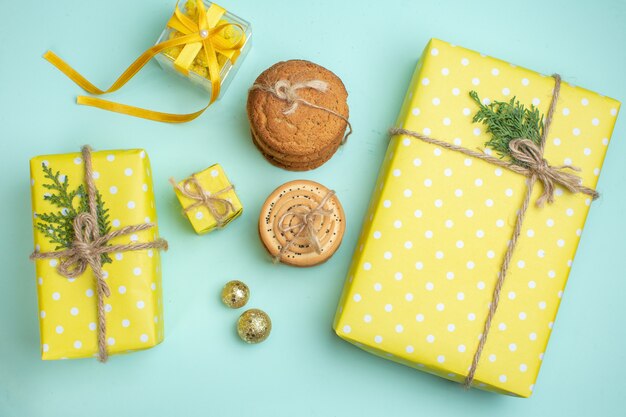 Empilhados vários biscoitos deliciosos e lindas caixas de presente amarelas ao lado do acessório de decoração em fundo verde pastel