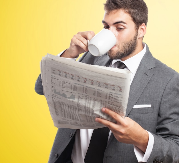 Empregado bebendo café enquanto lê o jornal