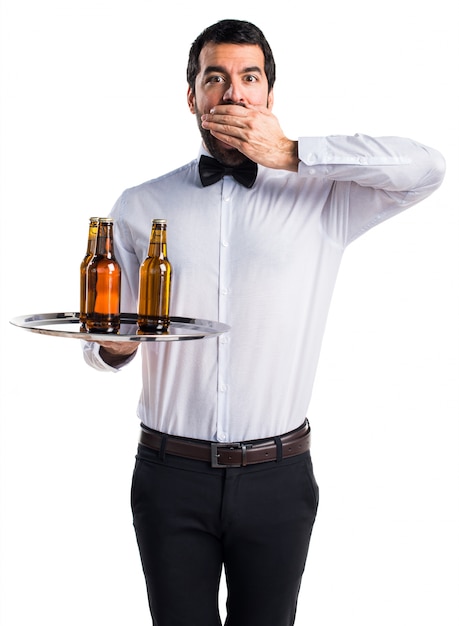 Foto grátis empregado de mesa com garrafas de cerveja na bandeja fazendo um gesto de surpresa