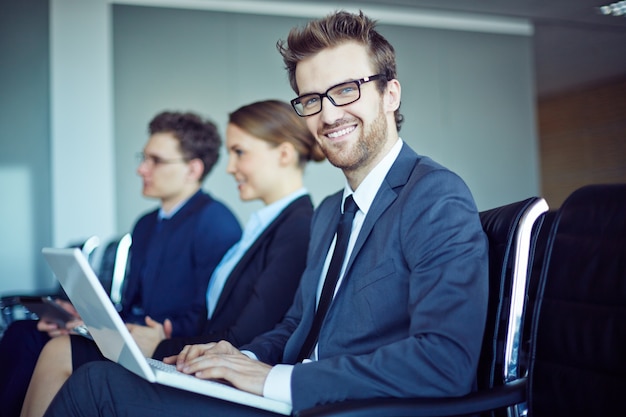 Empregado sorrindo com laço e laptop