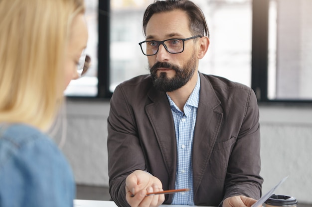 Empregador de homem barbudo bem-sucedido entrevista mulher para emprego