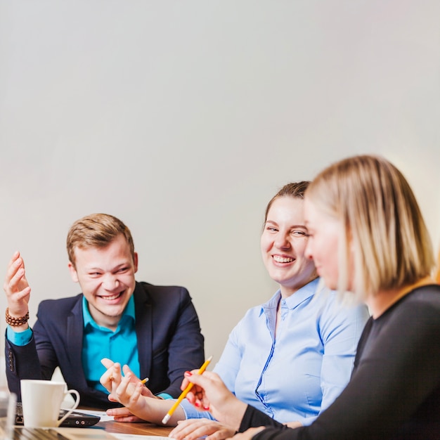 Empregados do escritório sentados na mesa, sorrindo