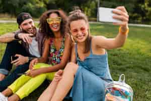 Foto grátis empresa jovem e elegante e colorida de amigos sentados no parque, homens e mulheres se divertindo juntos