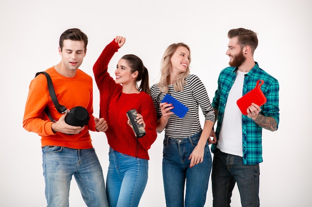 Empresa jovem hippie de amigos se divertindo juntos, sorrindo, ouvindo música em alto-falantes sem fio, dançando rindo na parede branca isolada com roupa colorida e elegante