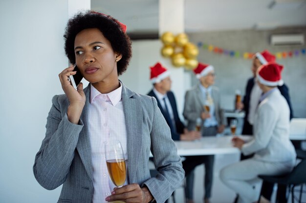 Empresária afro-americana pensativa falando ao telefone na festa de Ano Novo no escritório