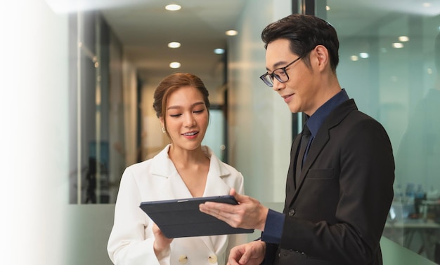 Foto grátis empresária asiática sorridente mostrando tablet para seu gerente durante uma reunião no escritório