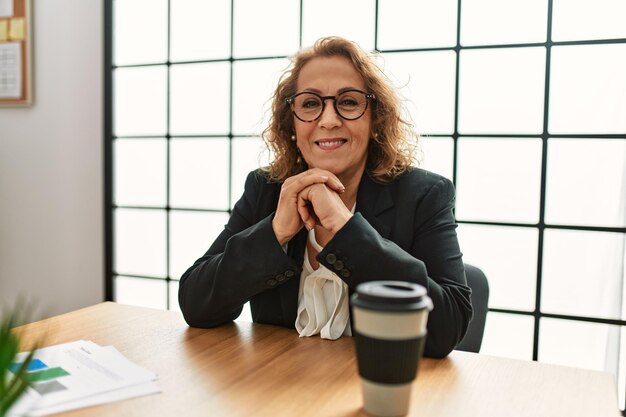 Empresária caucasiana de meia-idade sorrindo feliz trabalhando no escritório.