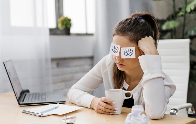 Empresária cobrindo os olhos com olhos desenhados no papel