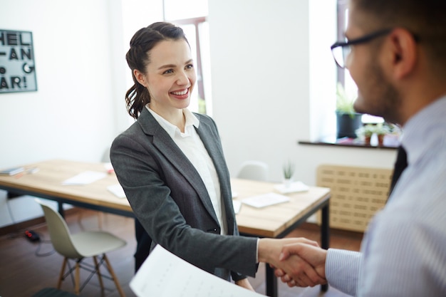 Empresária e empregado, apertando as mãos