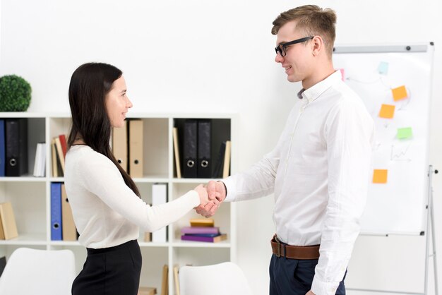 Empresária e empresário apertando as mãos uns dos outros no escritório