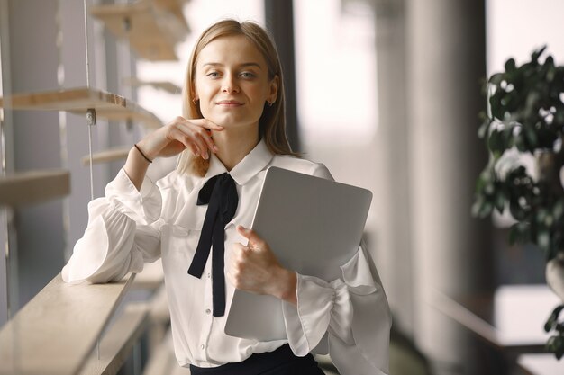 Empresária em pé no escritório com um laptop