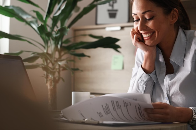 Foto grátis empresária feliz analisando relatórios de negócios e se sentindo satisfeita com o progresso dos negócios