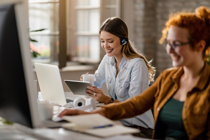 Foto grátis empresária feliz com fone de ouvido bebendo café enquanto navega na net no touchpad no escritório