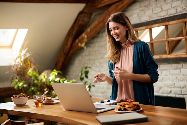 Empresária feliz tendo videochamada no laptop enquanto trabalhava em casa