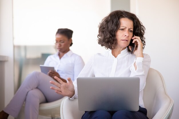 Empresária irritada, conversando com o parceiro no telefone