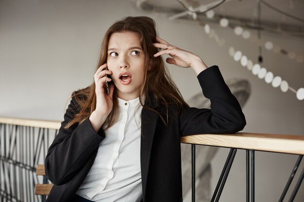 Empresária jovem preocupada no café falando por telefone