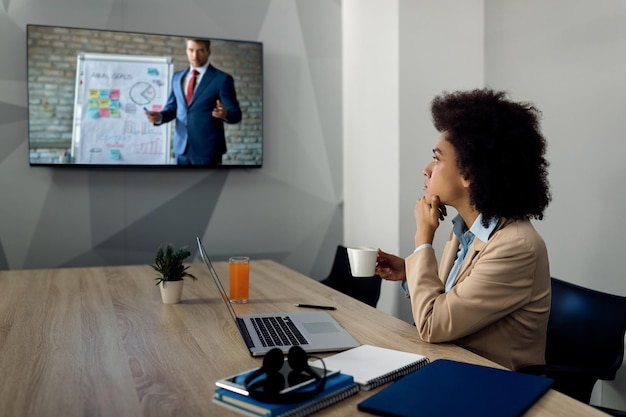 Empresária negra ouvindo seminário de negócios on-line via teleconferência no escritório