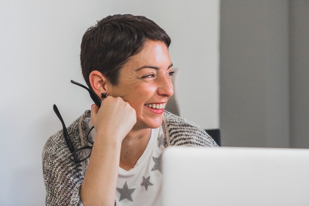 Empresária rindo enquanto, segurando seus óculos com a mão direita