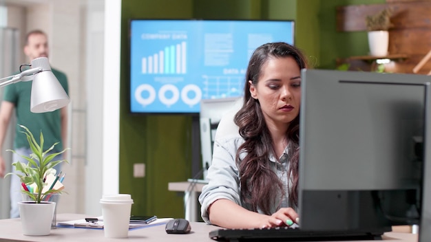 Empresária, sentada na mesa, digitando a estratégia de marketing usando o teclado do computador, trabalhando na apresentação do negócio. Gerente executivo analisando projeto de gestão no escritório da empresa startup