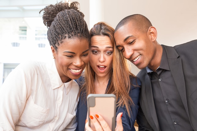 Empresária surpresa e colegas sorridentes tomando selfie