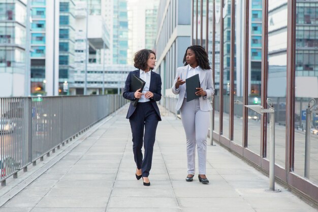 Empresárias, caminhando e conversando na rua