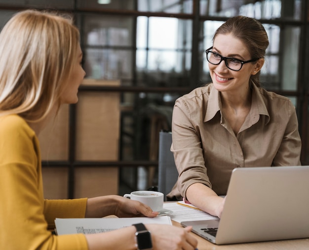 Empresárias sorridentes trabalhando com laptop na mesa