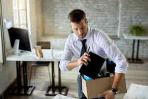 Foto grátis empresário adulto médio sendo demitido e arrumando suas coisas no escritório