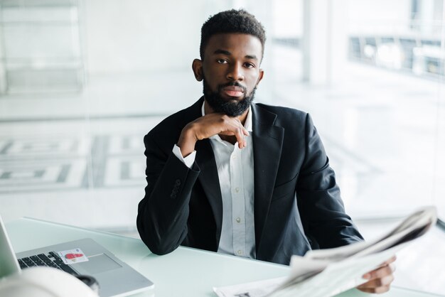 Empresário americano africano bonito com jornal perto do escritório do centro de negócios