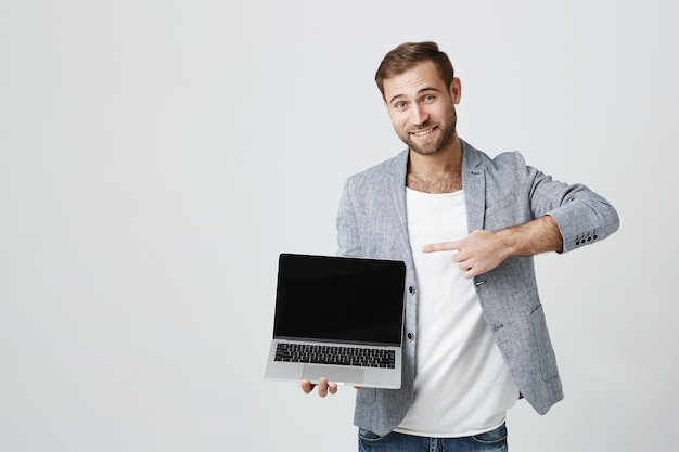 Empresário bonito apontando para a tela do laptop