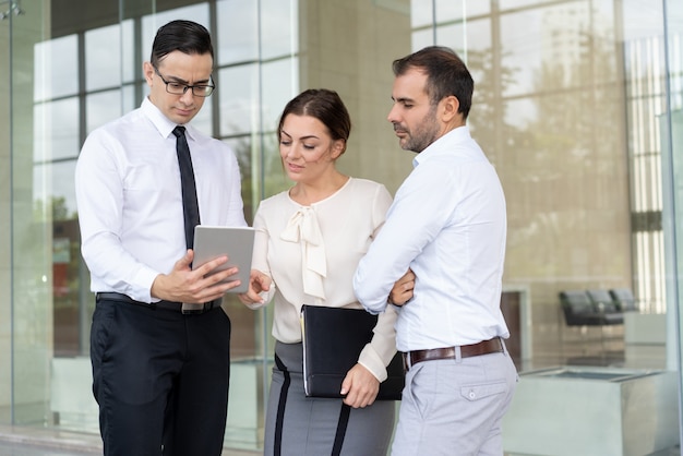 Empresário bonito mostrando dados no computador tablet para colleag