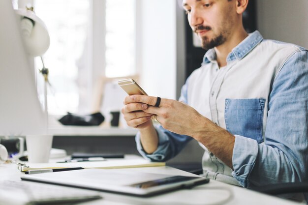 Empresário bonito trabalhando no escritório usando telefone celular