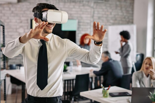 Empresário brincalhão usando fone de ouvido de realidade virtual e se divertindo no escritório Há pessoas no fundo