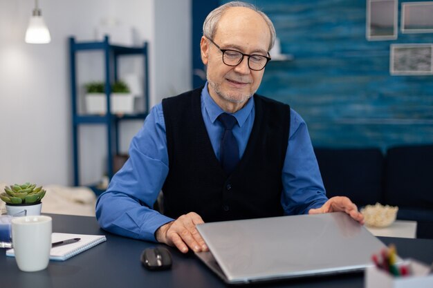 Empresário com cabelos grisalhos abrindo laptop