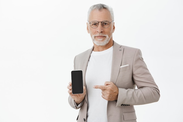 Empresário de terno e óculos apontando o dedo para a tela do celular
