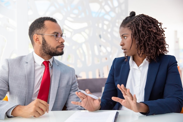 Empresário e empresária discutindo contrato